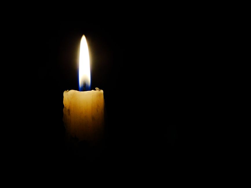 Dramatic close-up of a solitary candle flame against a black background.
