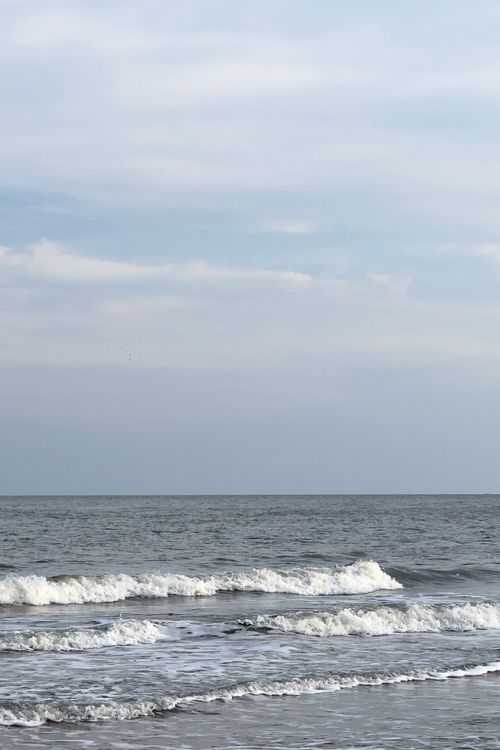 Free Tranquil overcast sea with gentle waves at the coast, perfect for calming backgrounds. Stock Photo