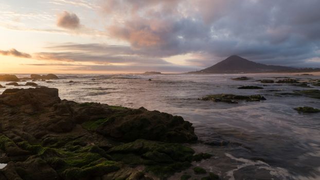 Breathtaking sunset view of Moledo Beach with rugged coastline and distant hills.