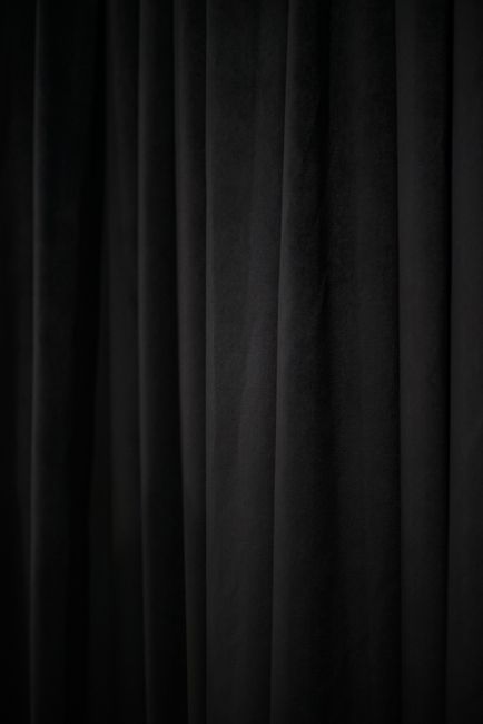 A close-up of elegant black fabric with vertical folds, showcasing texture and monochrome style.