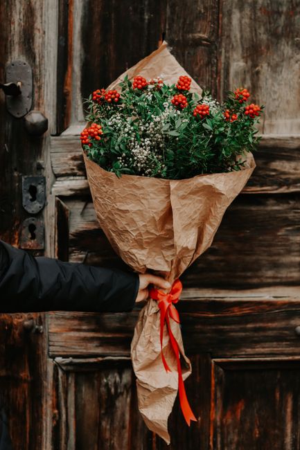 Charming rustic bouquet with red berries and greenery against a wooden door, perfect for eco-friendly themes.
