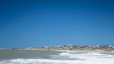 A picturesque coastal view of Punta del Diablo, Uruguay with vibrant blue skies and waves.