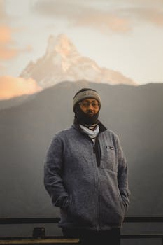 Man in Ghandruk, Nepal with the Himalayas in the background, wearing a gray jacket and beanie.