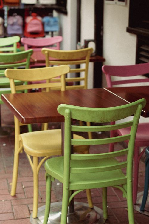 Free Colorful wooden chairs and tables arranged in an outdoor cafe setting. Stock Photo