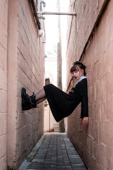A woman in a black dress hangs between alley walls in urban Orlando, Florida.