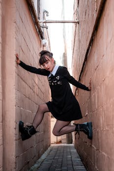 A young woman in a black dress striking a pose in a narrow urban alley, Orlando, FL.