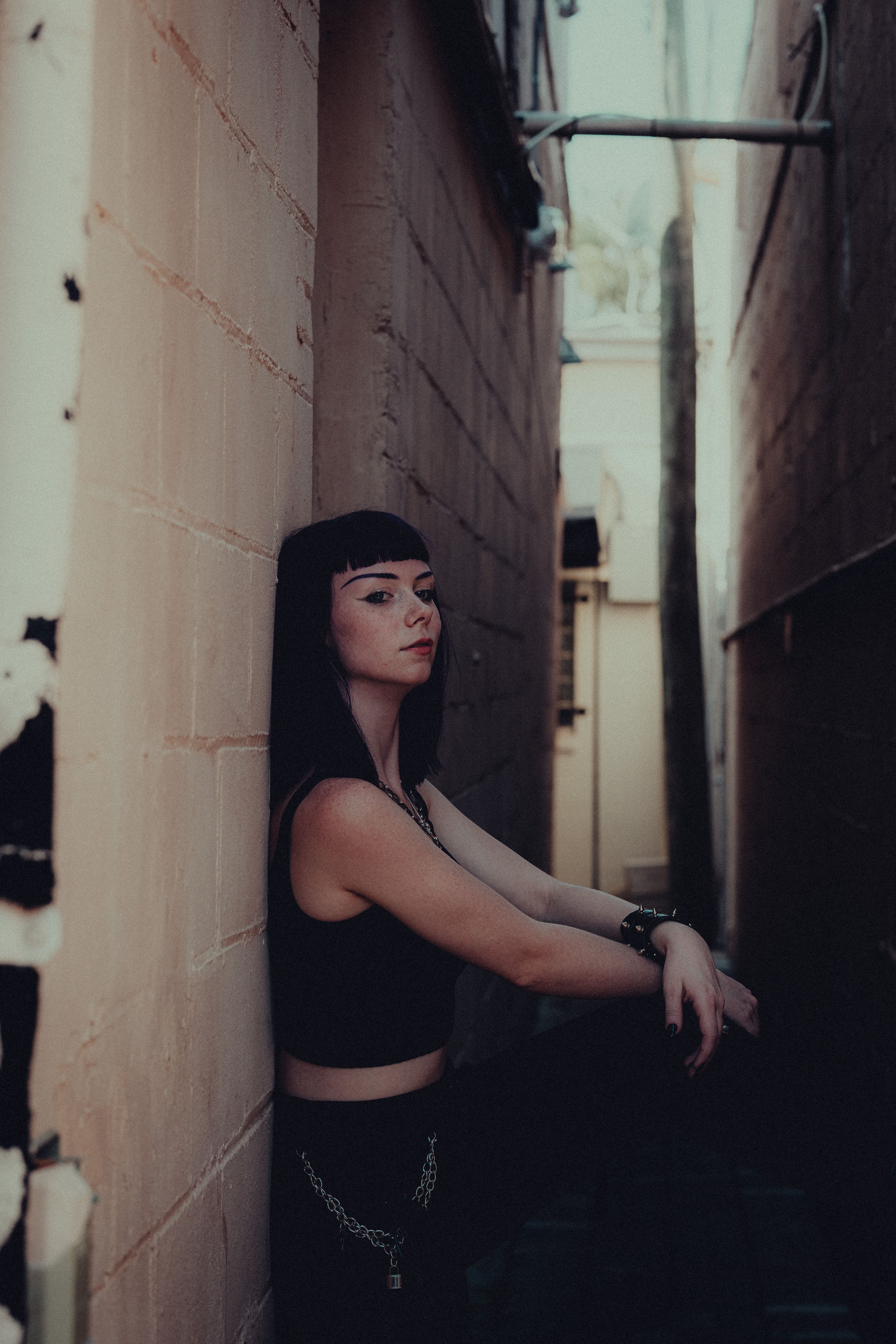 A woman in black pants and a crop top leaning against a wall · Free ...
