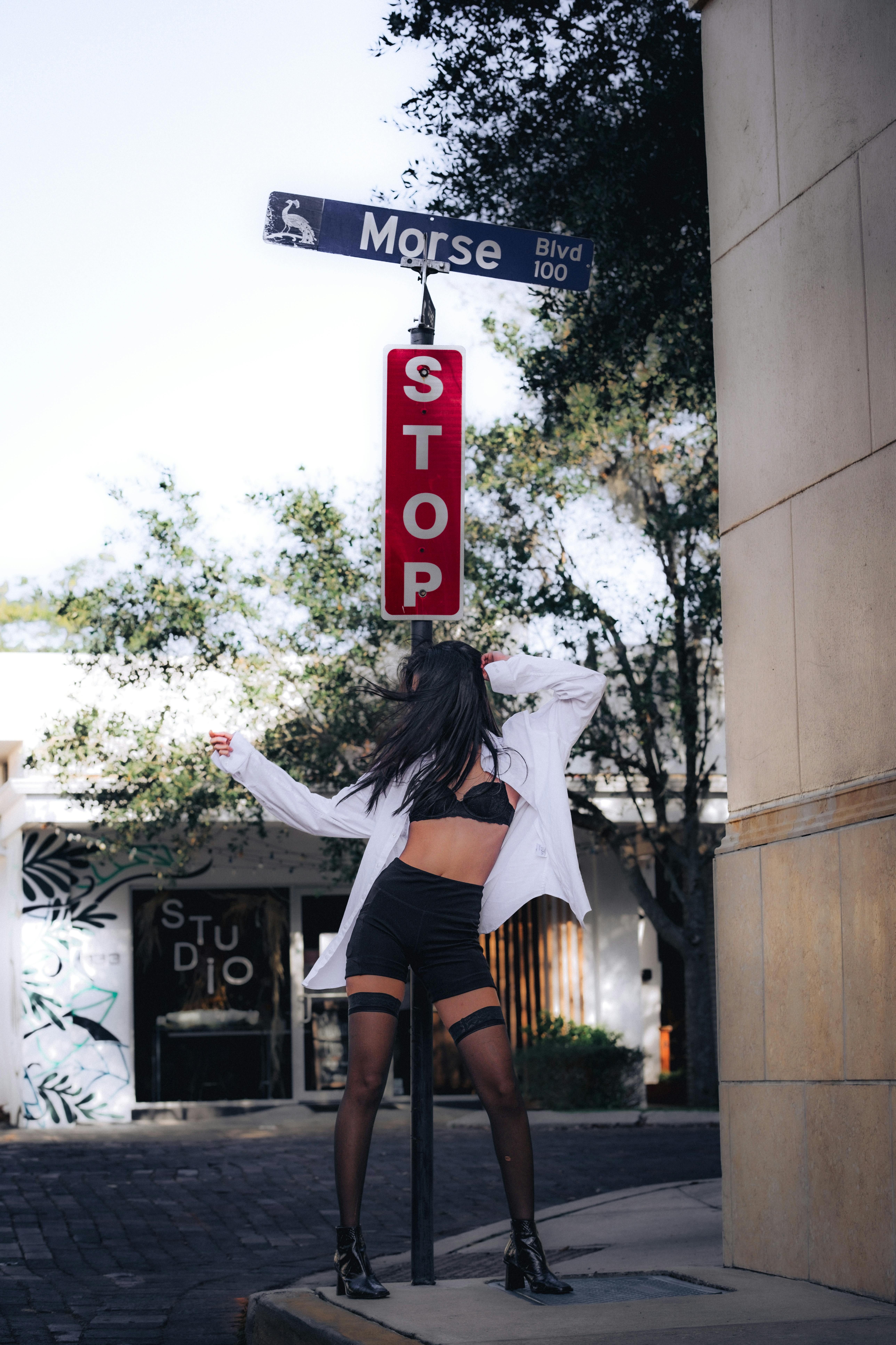 a woman in a short skirt and stockings posing next to a stop sign