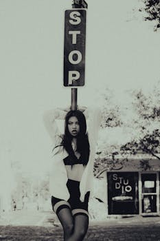A dramatic and moody black and white street portrait in Orlando, featuring a stylish woman by a stop sign.