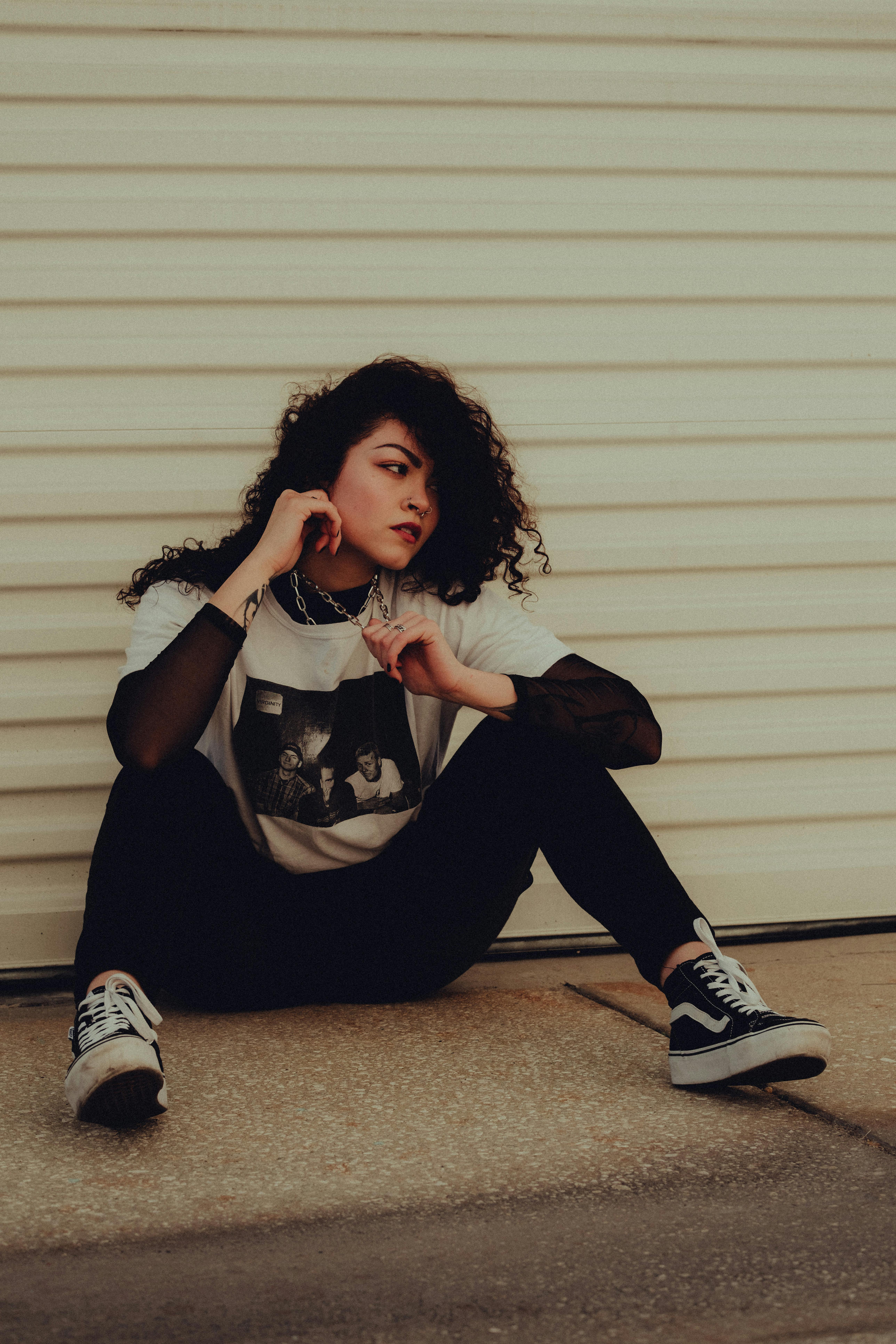 a girl sitting on the ground with her hands on her knees