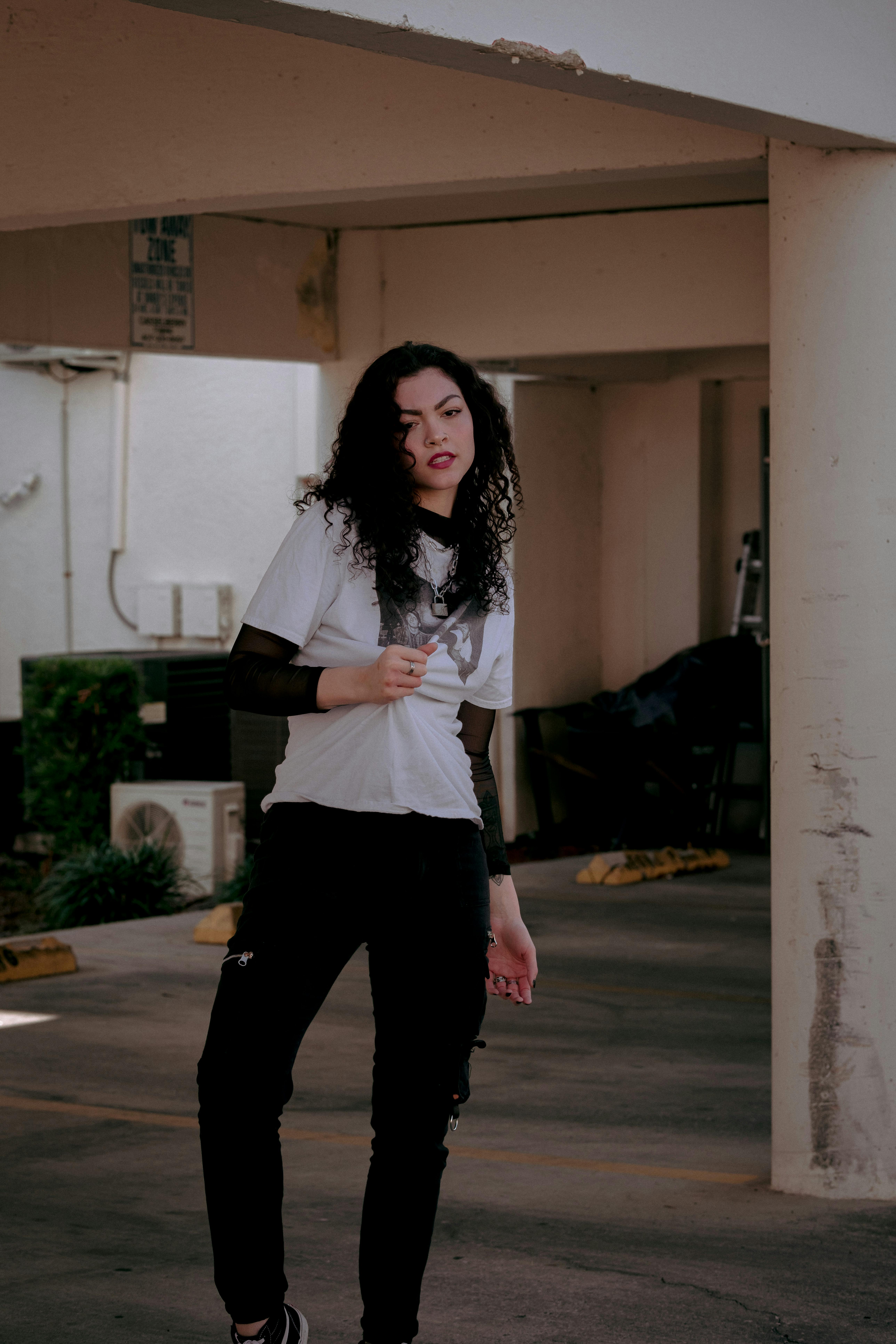 a woman in black pants and white shirt standing in a parking garage