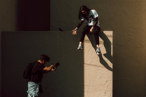 A Photographer Taking a Picture of a Woman Sitting on a Concrete Wall