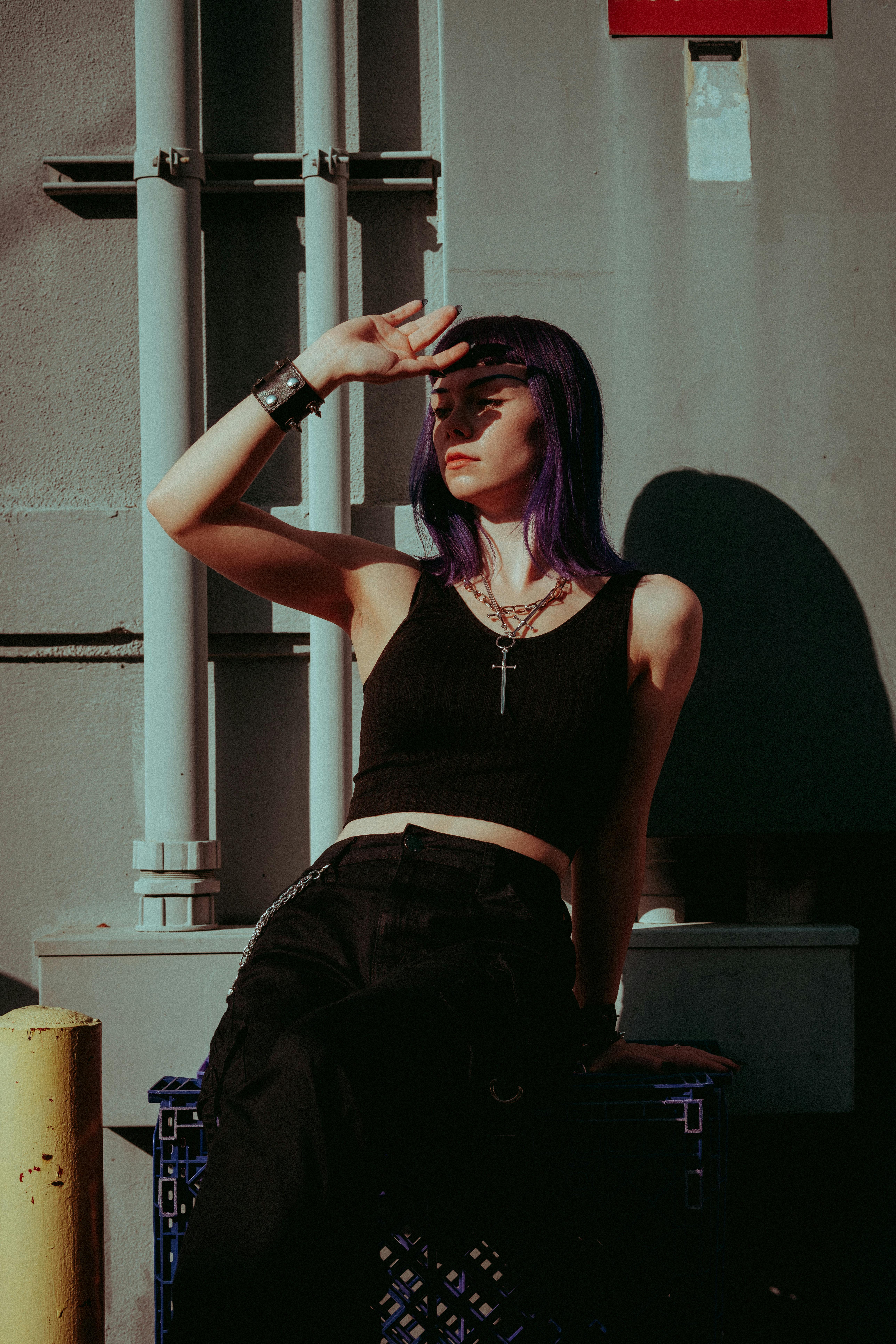 a woman with purple hair sitting on a bench