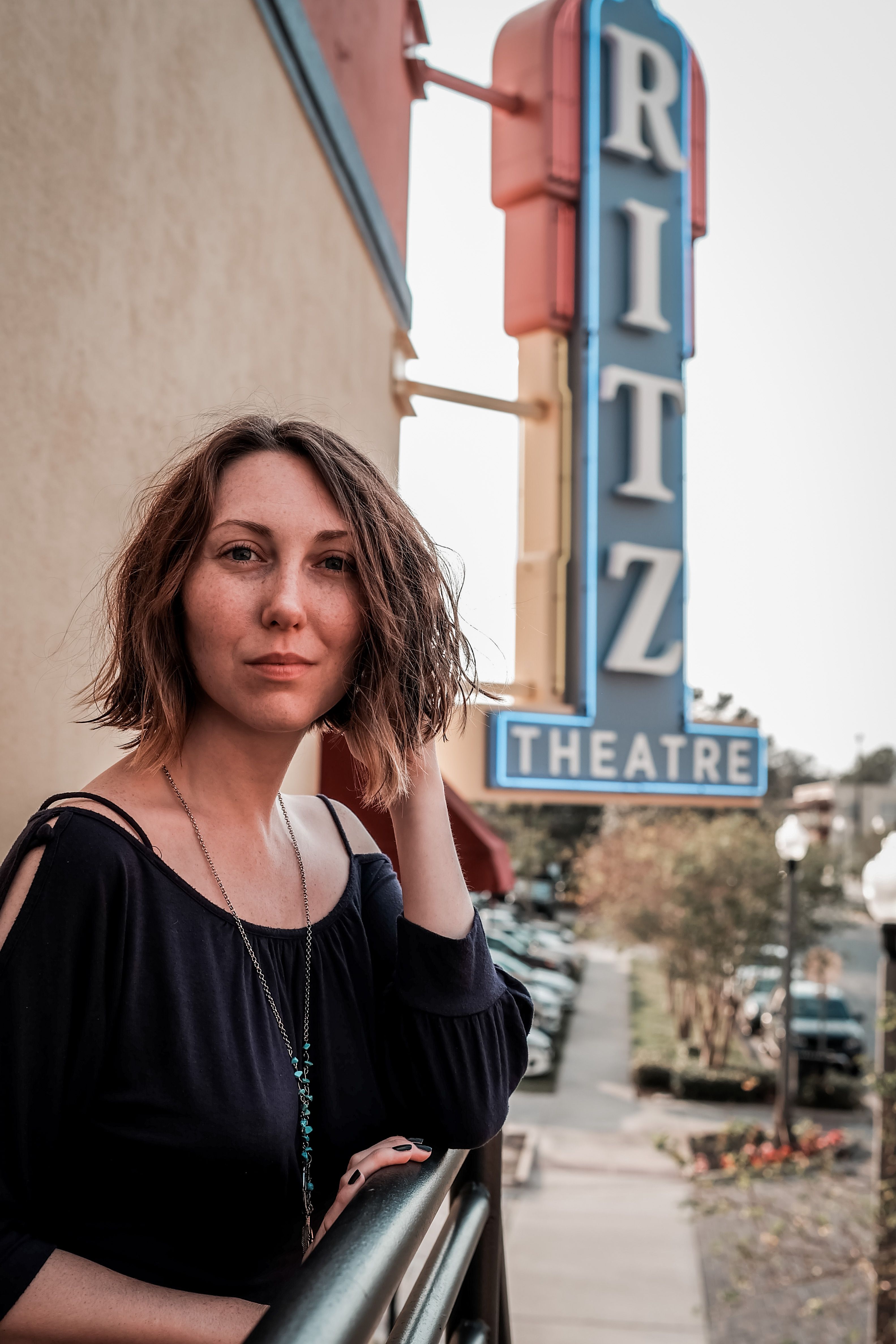 Portrait of a woman standing by Ritz Theatre in Sanford, FL, showcases vibrant street style and natural beauty.