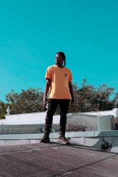 Dynamic urban portrait of a young man in vibrant clothing, set against a city backdrop.