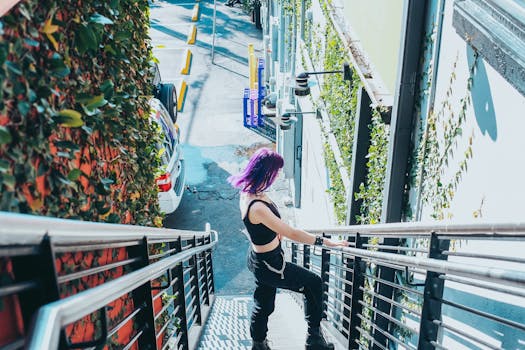 A woman with vibrant purple hair descends a staircase in an urban setting, exuding a modern and fashionable vibe.