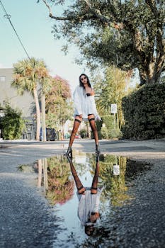 Fashionable woman in Orlando reflected in a street puddle, embodying urban chic style.