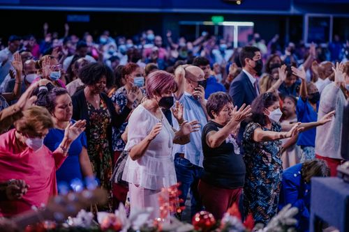 Free A large, diverse group of people praying and worshipping together indoors, wearing face masks. Stock Photo