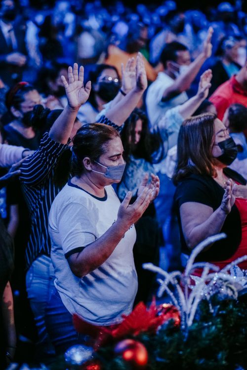 Free A diverse group of adults standing together, raising hands in a blue-lit indoor event. Stock Photo