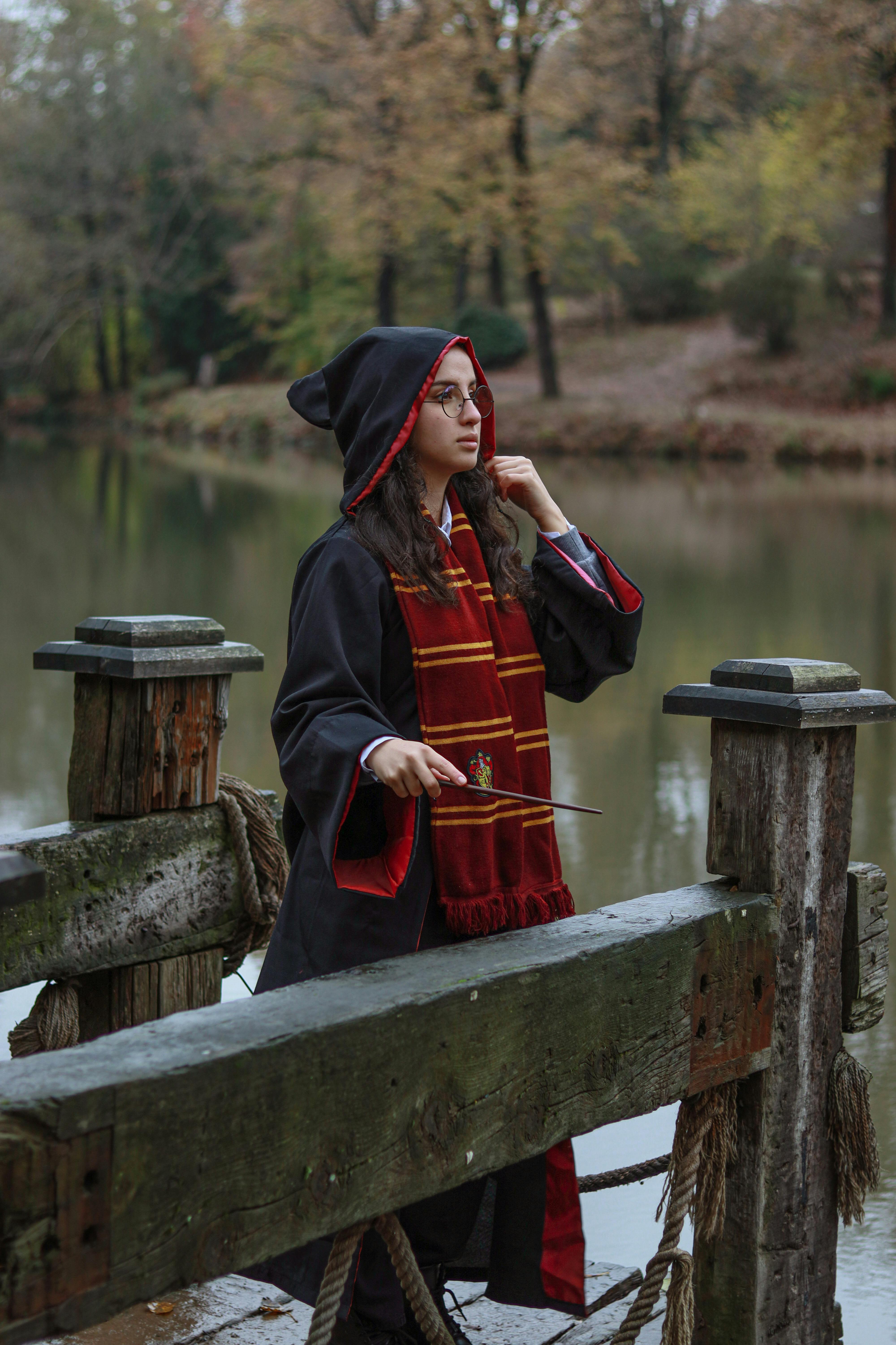 a woman in a harry potter robe standing on a dock