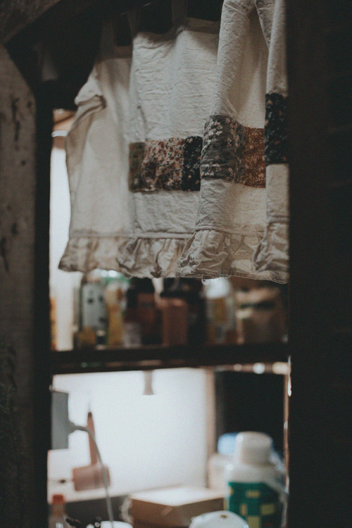 Free Cozy vintage kitchen scene featuring hanging textiles and blurred background shelves. Stock Photo