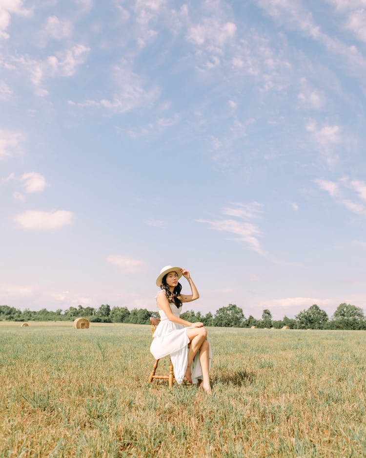 Woman Sitting In Grassfield In Summer