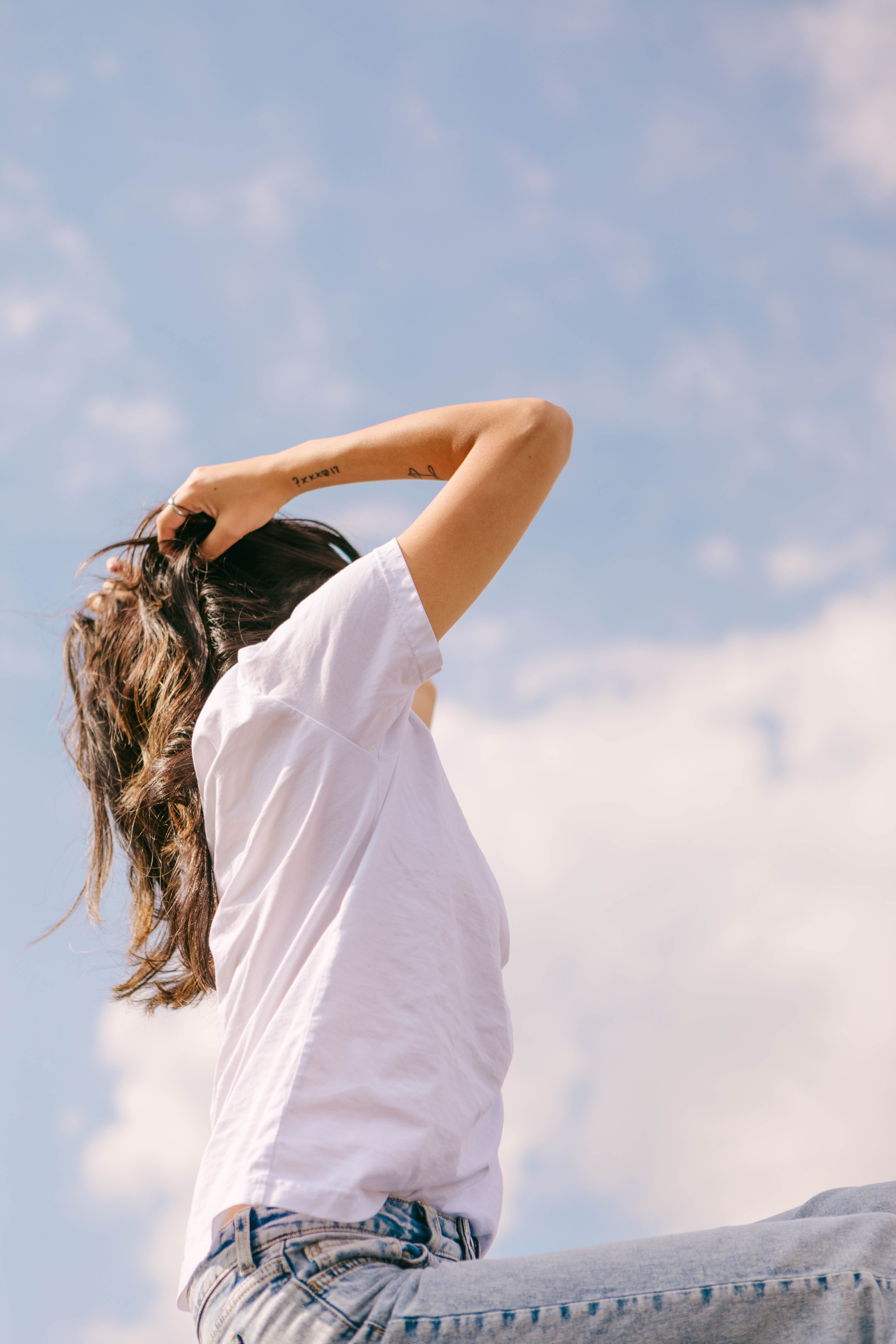 A Woman in White Shirt Holding Her Hair · Free Stock Photo