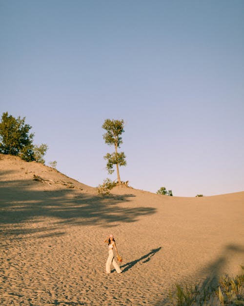 A Woman Walking on Brown Sand