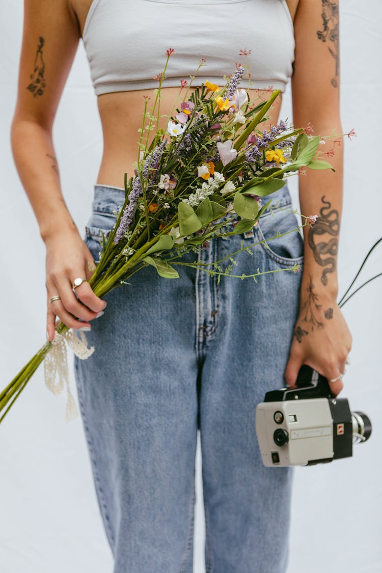 Woman In Jeans Holding Vintage Camera And Flowers