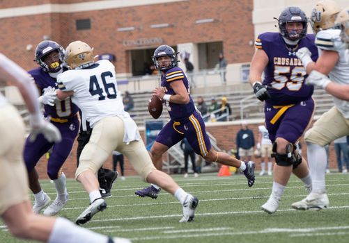 Dynamic action shot of a college football game with players in motion, showcasing teamwork and competition.