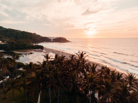 Aerial view of a serene tropical beach at sunset with palm trees and calm waves in San Francisco, Nayarit, México.