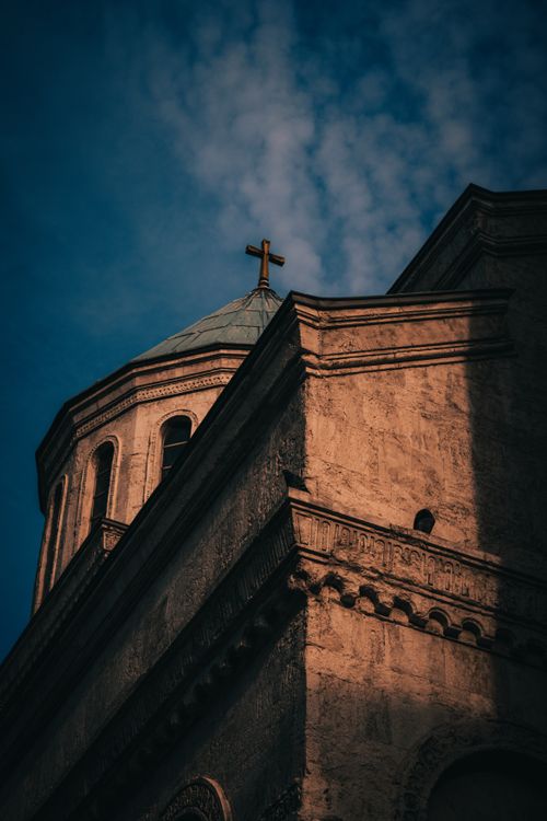 Free A stunning low-angle view of a church in İstanbul with intricate architectural details and a golden cross against the blue sky. Stock Photo