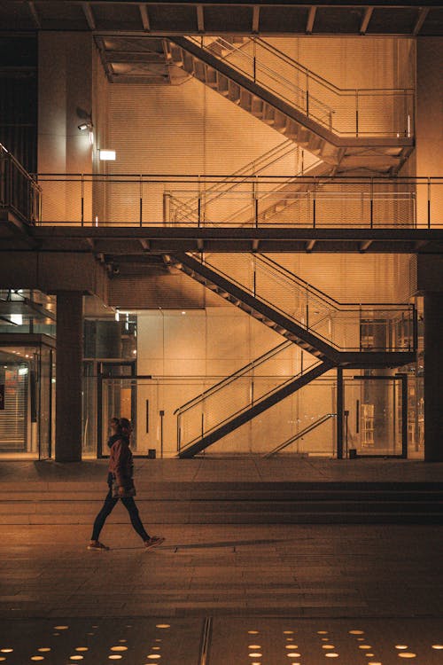 Woman Passing By a Modern Building in City at Night 