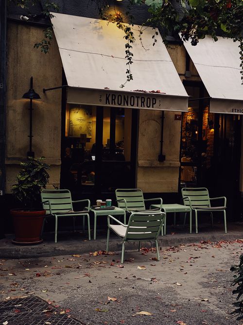 Free A charming café with mint green chairs and warm lighting creates a cozy urban seating area. Stock Photo