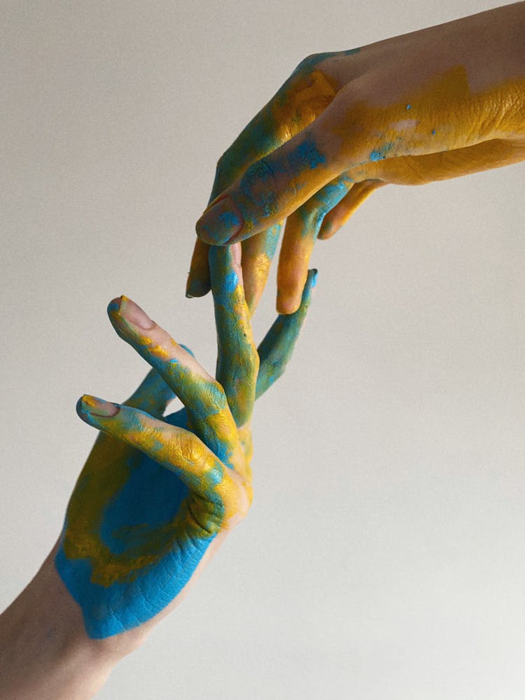 Hands Covered In Blue And Yellow Paint Touching