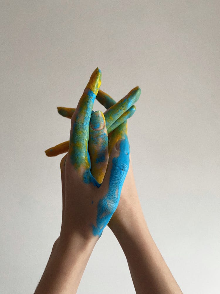 Hands Painted Yellow And Blue Intertwining Fingers