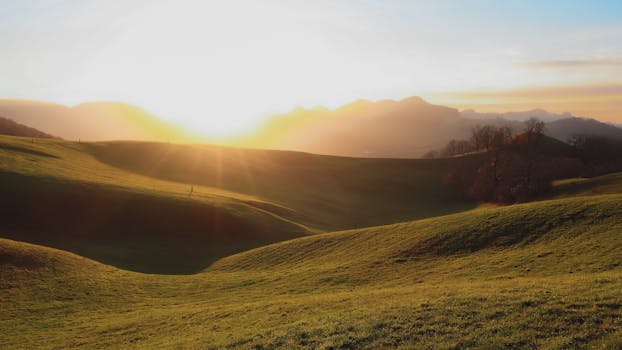 Captivating view of rolling green hills under a dramatic sunset, showcasing nature's serene beauty.