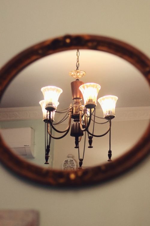 Free A stylish chandelier is beautifully reflected in an ornate mirror, creating a warm, inviting ambiance. Stock Photo