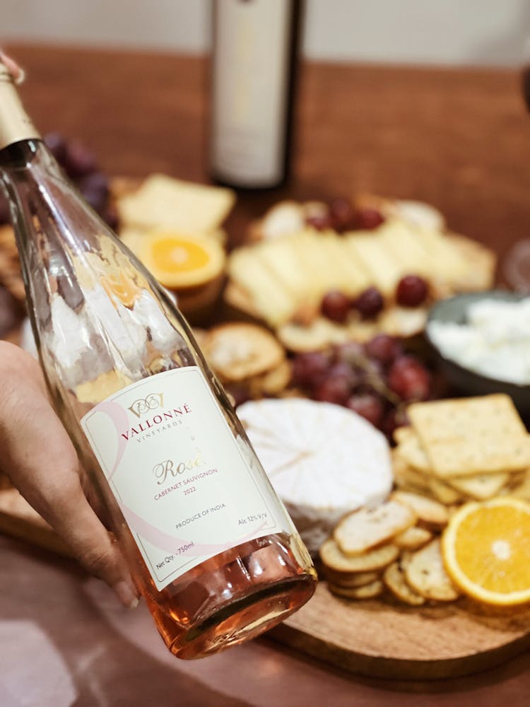 Bottle Of A Pink Wine With Cheese And Fruits Board