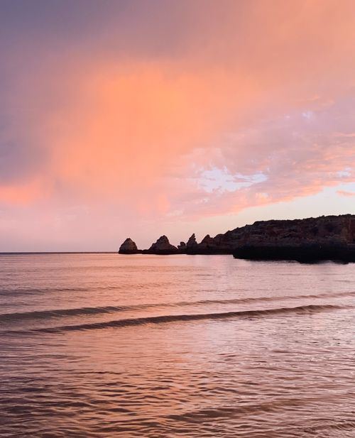 Free Tranquil ocean scene at sunset with vibrant skies and gentle waves on a quiet beach. Stock Photo