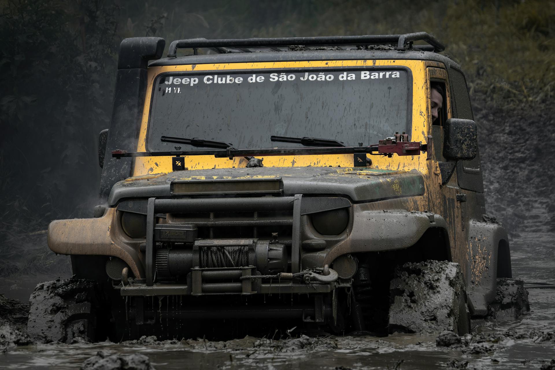 A rugged Jeep navigates through thick mud, showcasing its off-road capabilities.