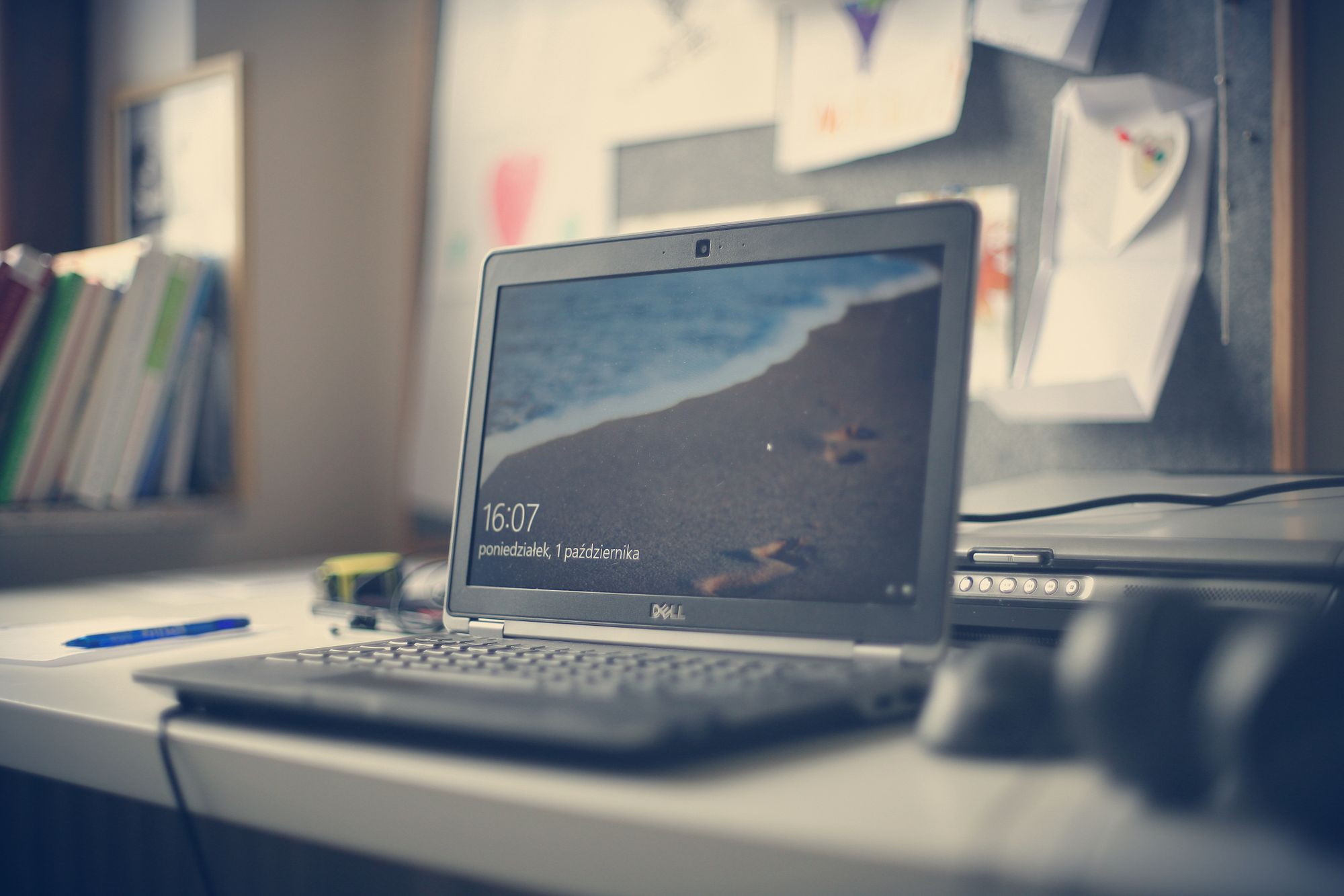 Laptop abierta sobre un escritorio de madera con el teclado en primer plano y la pantalla encendida