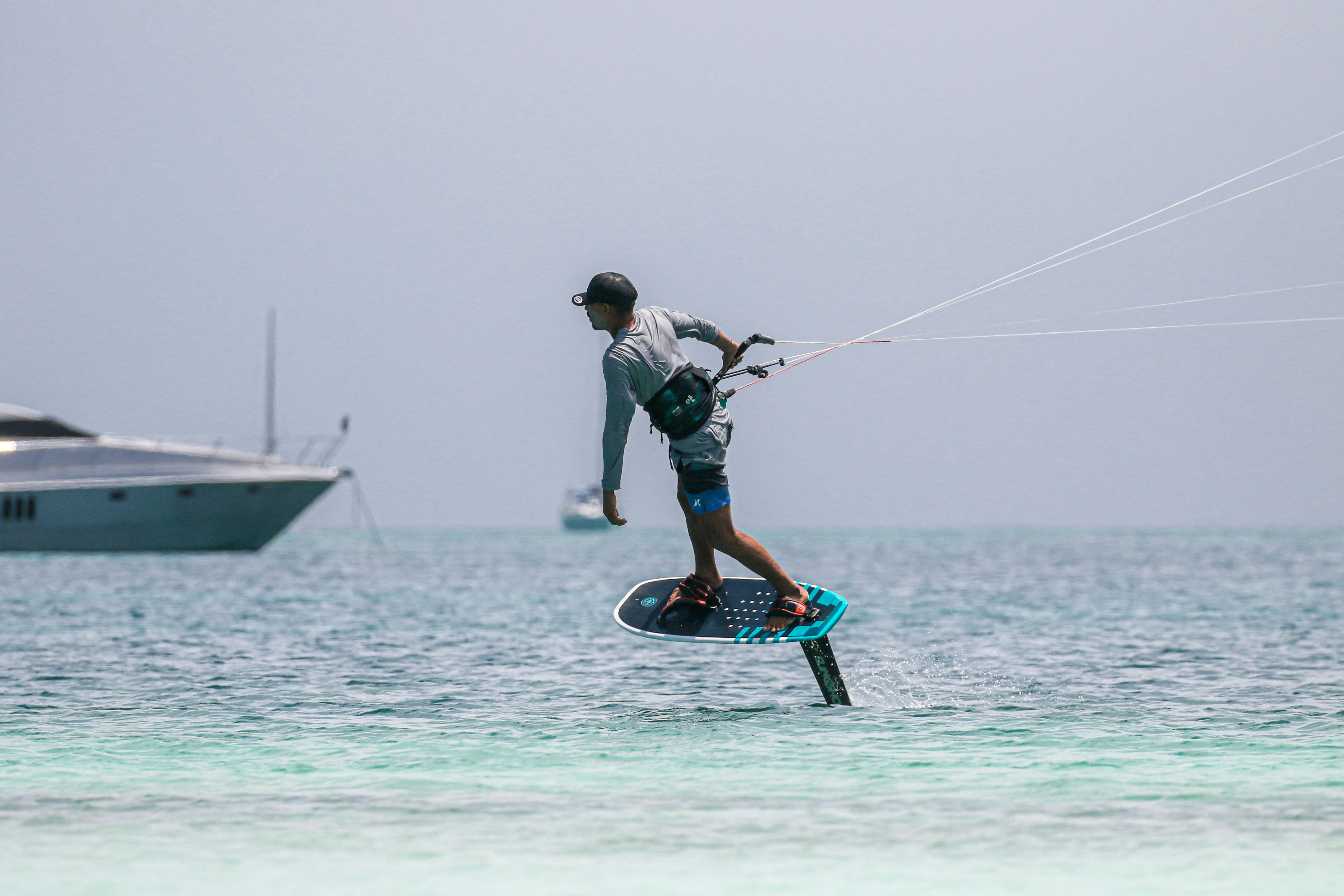 Prescription Goggle Inserts - Dynamic kitesurfing scene with a surfer soaring over the ocean, beside a yacht.