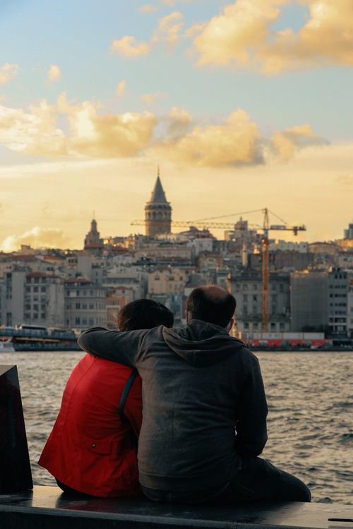 Free Couple embracing by the river with Galata Tower in view, Istanbul, at sunset. Stock Photo