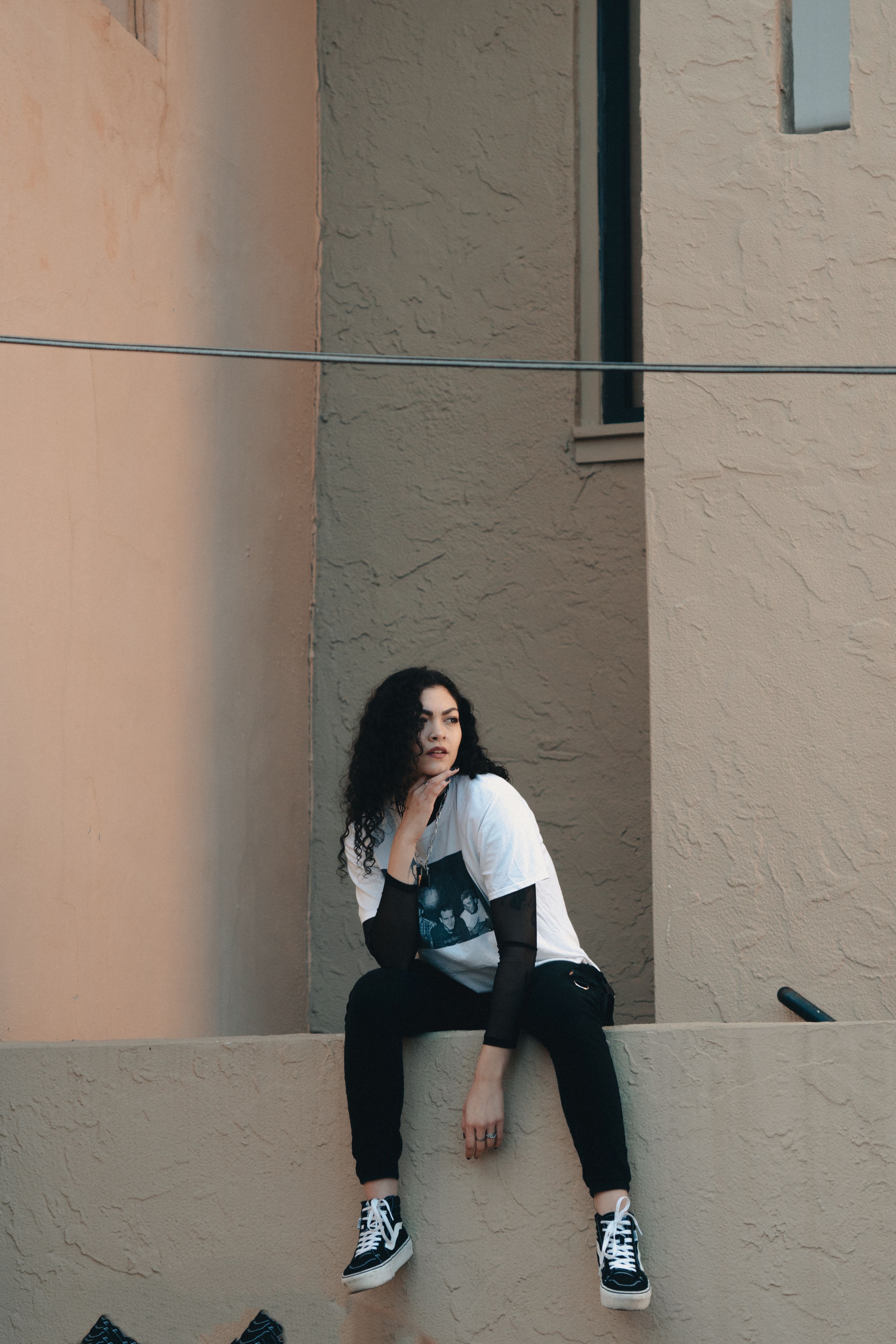 A Woman Posing while Sitting on the Concrete Wall · Free Stock Photo