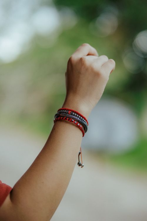 Free A raised arm adorned with vibrant woven bracelets against a soft, natural background. Stock Photo