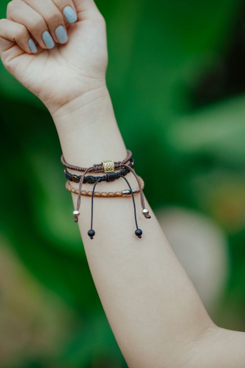 Free Close-up of a stylish leather bracelet on a female arm against a lush green background. Stock Photo