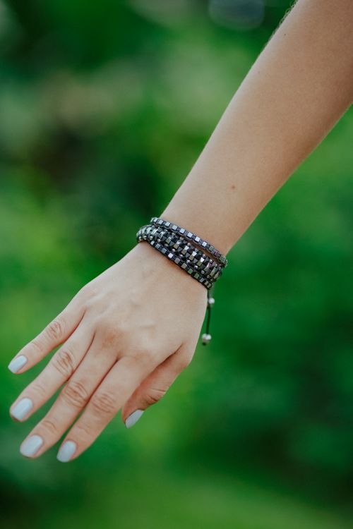 Free Close-up of a woman's hand wearing a fashionable bracelet against a lush green background. Stock Photo