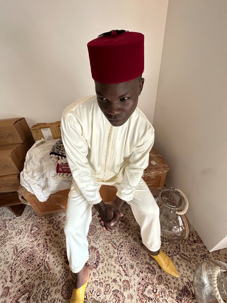 Boy In Hat Sitting In Room Corner