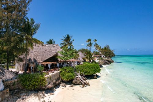 Free Beautiful tropical beach resort in Zanzibar, Tanzania, with thatched huts, palm trees, and turquoise waters. Stock Photo